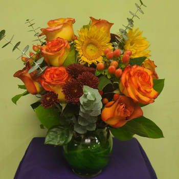 Orange and yellow roses with sunflowers in a glass vase