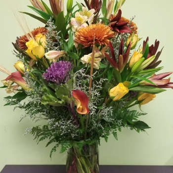 Mixed bouquet of lilies, roses, calla lilies, and chrysanthemums in a glass vase