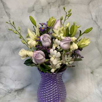 Lavender roses and white lilies in a purple textured vase