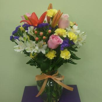 Mixed bouquet of lilies, roses, and carnations in a glass vase