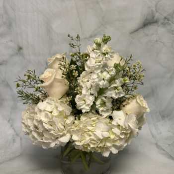 White roses and hydrangeas arranged in a glass vase