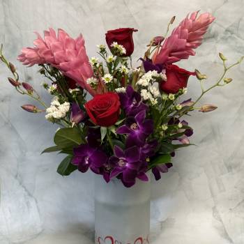 Bouquet of red roses and purple orchids in a heart-decorated vase
