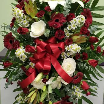 Large standing floral spray with red and white flowers and a red ribbon bow