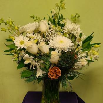 White flowers arranged in a clear glass vase with greenery