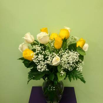 Yellow and white roses in a glass vase with baby's breath
