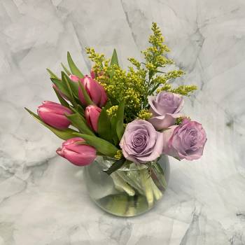Pink tulips and lavender roses in a clear glass vase