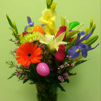 Colorful mixed bouquet in a clear glass vase with decorative eggs
