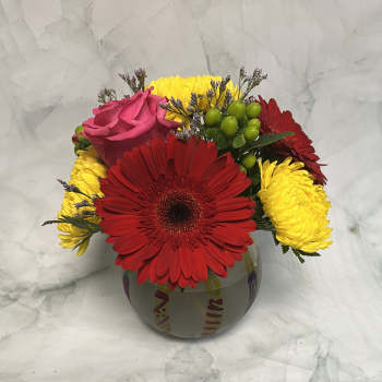 Bouquet of red gerbera daisies, yellow mums, and a pink rose in a round vase