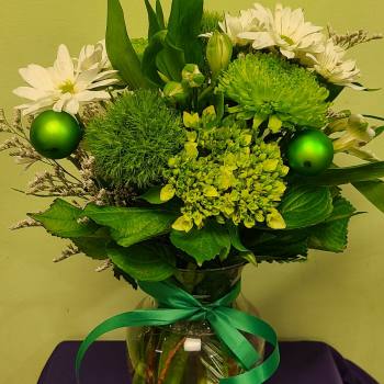 Green and white bouquet in a glass vase with a ribbon