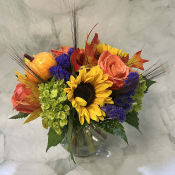 Sunflower and rose arrangement in a glass vase with autumn accents