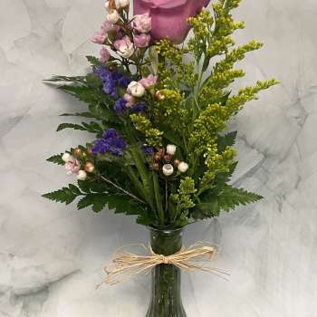Pink rose bouquet in a clear glass vase with small purple and white flowers