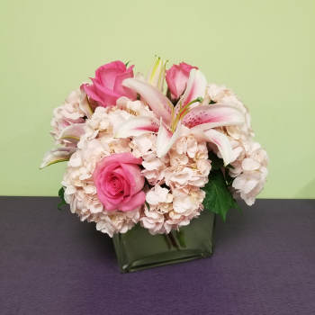 Pink roses and white lilies arranged in a square glass vase