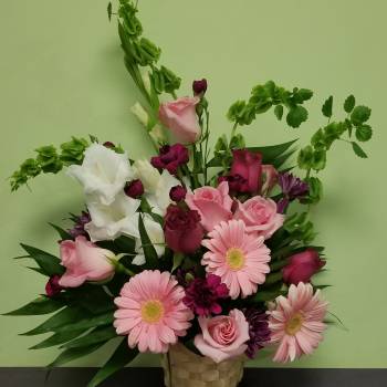 Pink and white mixed flower arrangement in a woven basket