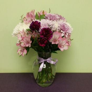 Pink and white mixed bouquet in a glass vase with a lavender ribbon