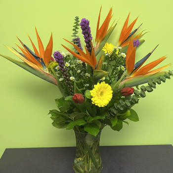 Bouquet of orange bird of paradise and mixed flowers in a glass vase