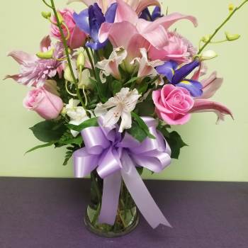 Pink and purple mixed bouquet in a glass vase with a lavender ribbon