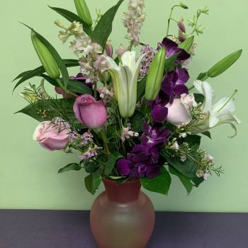 Mixed bouquet of lilies, roses, and purple orchids in a vase