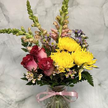 Mixed bouquet with yellow chrysanthemums, pink roses, and a glass vase tied with ribbon
