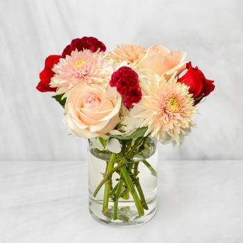 Bouquet of pale pink and red flowers in a clear glass vase