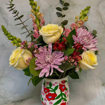 Bouquet of yellow roses, pink chrysanthemums, and red alstroemeria in a painted vase