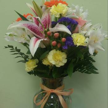 Mixed bouquet in a glass vase with lilies, carnations, and daisies