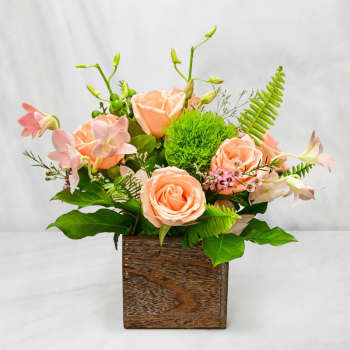 Peach roses and pink orchids in a wooden box arrangement