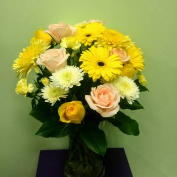 Bouquet of yellow and pale pink flowers in a glass vase