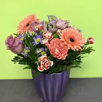 Mixed bouquet of pink and purple flowers in a purple vase