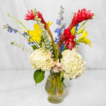 Mixed bouquet with red and yellow tropical flowers in a glass vase