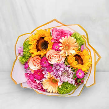 Bouquet of sunflowers, pink roses, and gerbera daisies wrapped in white paper