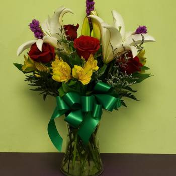 Bouquet of red roses, white lilies, and yellow alstroemeria in a glass vase