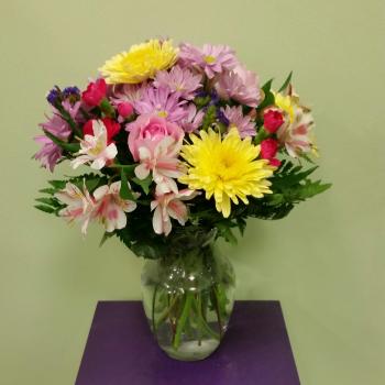 Mixed bouquet of daisies, roses, and alstroemeria in a glass vase