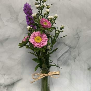 Pink and white flowers in a tall glass vase tied with raffia