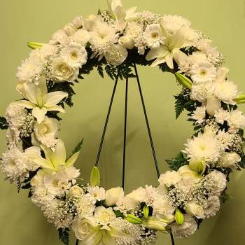 White floral wreath on a black stand