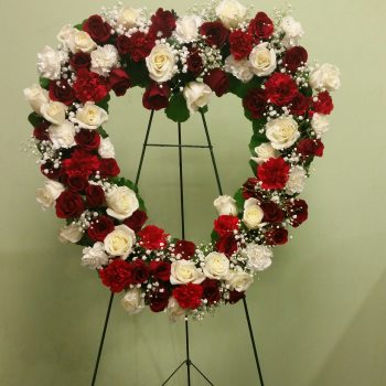 Heart-shaped floral wreath of red and white roses on a stand