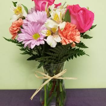 Bouquet of pink roses, lavender daisies, and white alstroemeria in a glass vase
