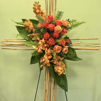 Orange roses and orchids arranged on a bamboo cross stand