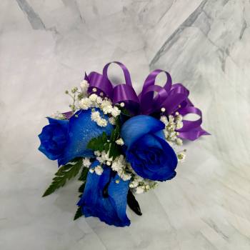 Blue roses with white baby's breath and a purple ribbon
