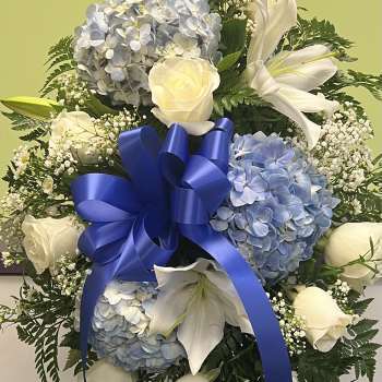 Blue and white floral standing spray with roses, hydrangeas, lilies, and a ribbon bow