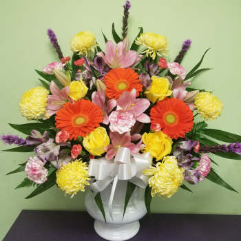 Colorful mixed bouquet in a white vase with a silver bow