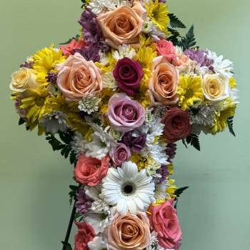 Cross-shaped floral arrangement with roses and daisies on a stand