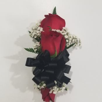 Two red roses with white baby's breath and a black ribbon