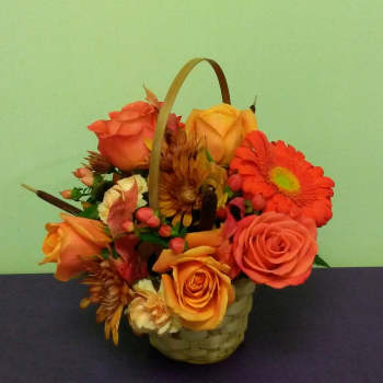 Basket arrangement of orange roses and gerbera daisies