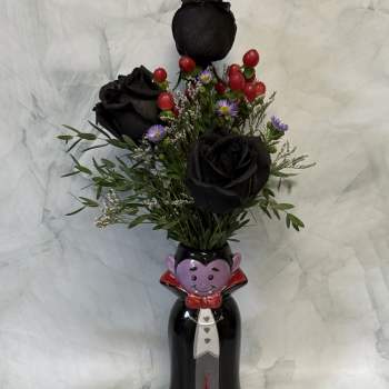 Black roses in a Halloween vampire vase with red berries