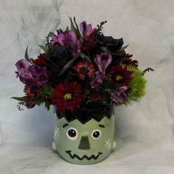Bouquet of red, purple, and black flowers in a Frankenstein face vase