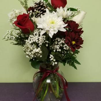 Bouquet of red roses, white chrysanthemums, and baby's breath in a glass vase