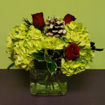 Yellow hydrangea arrangement with red roses in a glass vase