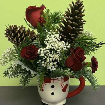Red roses and pinecones arranged in a snowman mug