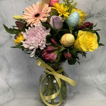 Mixed bouquet in a glass vase with pastel flowers and decorative eggs