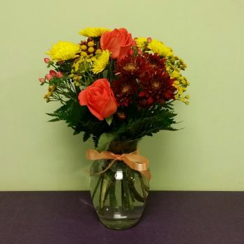 Bouquet of orange roses and yellow chrysanthemums in a glass vase